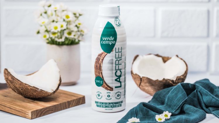 Bebida lacfree Verde Campo sabor coco em garrafa, acompanhada de coco aberto e elementos naturais em fundo claro.