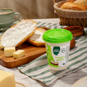 Requeijão cremoso Verde Campo em pote, servido com pão, manteiga e café em mesa de café da manhã.