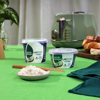 Queijo cottage lacfree Verde Campo em pote, servido em ambiente de cozinha com torradas, planta decorativa e tons verdes.